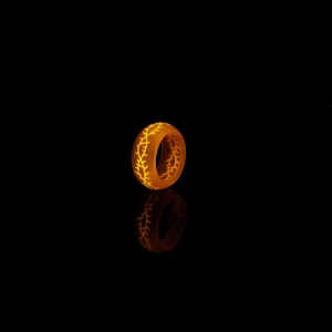 Détail d'une bague épines lumineuse avec lueur orange et texture en résine mate