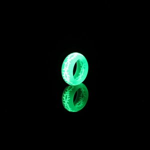 Détail d'une bague lumineuse en résine verte avec motifs d'épines brillant dans le noir
