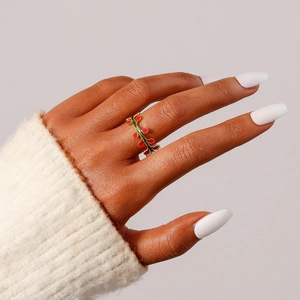Detailaufnahme eines Blattrings mit roten Beeren und Goldfinish am Finger für Damen
