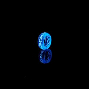 Vue détaillée d'une bague en résine lumineuse avec motif d'épines bleues dans le noir