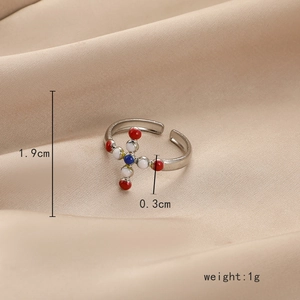 Bague réglable argentée avec croix colorée sur fond de satin beige élégant et luxueux