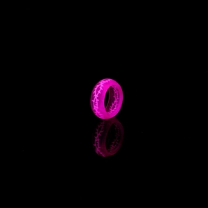 Détail d'une bague rose lumineuse avec texture épines brillant dans le noir