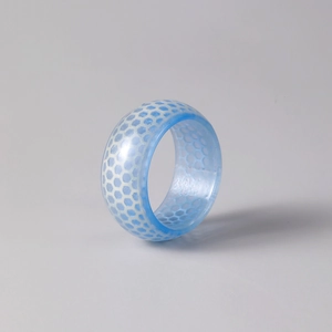 Detail eines blau leuchtenden Harzrings mit weißem sechseckigem Wabenmuster-Design