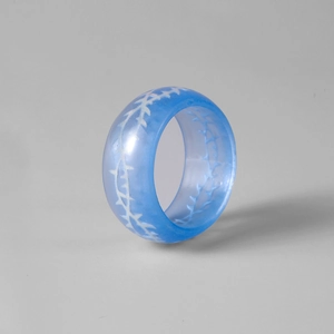 Détail macro d'une bague en résine bleue lumineuse avec motif d'épines blanches et polies