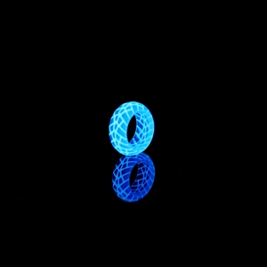 Makroaufnahme von leuchtendem Harzring mit blauem Gittermuster auf schwarzem Grund