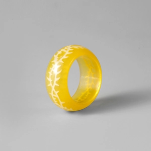 Détail d'une bague en résine jaune translucide avec motif d'épines blanches lumineuses