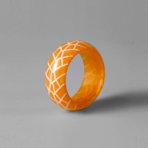 Detailansicht eines orangefarbenen Harzrings mit weißem Gittermuster-Design