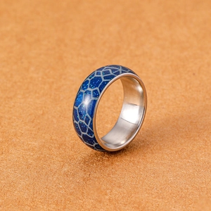 Makroaufnahme von blau leuchtendem Ring mit Edelstahl-Schlangenhautmuster Textur