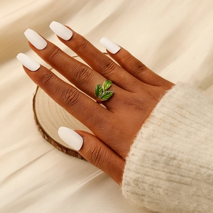 Nature-style gold leaf ring with green enamel leaves on a wooden display stand