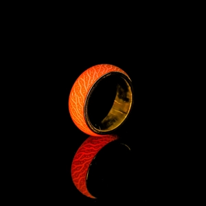 Leuchtender Edelstahlring mit orangefarbenem Zellmuster, der im Dunkeln hell strahlt