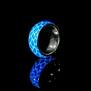 Leuchtender blauer Drachenschuppen-Ring mit Nachtleuchteffekt auf schwarzem Grund