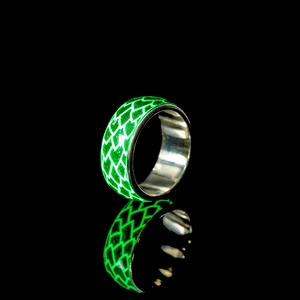 Makroaufnahme von leuchtendem Fischschuppen-Ring mit grünem Glow-Effekt aus Edelstahl