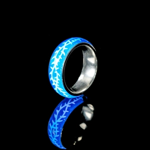 Im Dunkeln leuchtender blauer Ring mit weißem Rankenmuster auf schwarzem Hintergrund
