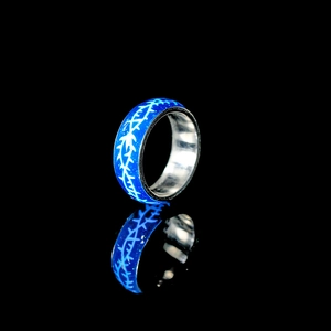 Blau leuchtender Ring mit weißen Dornenmustern auf einem schwarzen Hintergrund