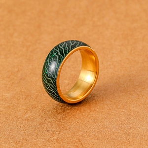 Detailaufnahme des leuchtenden grünen Rings mit goldener Innenseite auf Stoffuntergrund