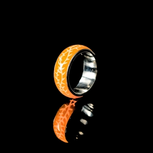 Makroaufnahme: Oranger Emaille-Ring mit weißen Dornenmustern und polierter Stahl-Innenseite