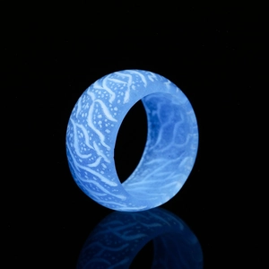 Glow-in-the-dark blue resin ring with intricate white vine textures on black background