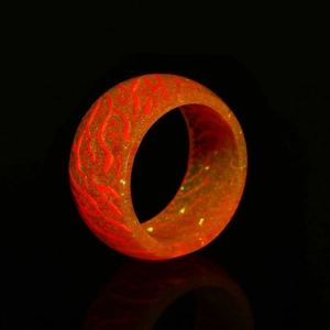 Macro view of luminous resin ring with glowing red lava texture and golden glitter