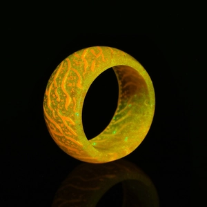 Detailed view of glowing orange resin ring with wood grain texture in dark background
