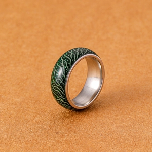 Makro-Detail des grün leuchtenden Crackle-Musters auf dem Edelstahl-Ringband