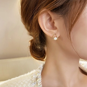 Elegant gold drop teardrop earrings with central pearl on model, minimalist style