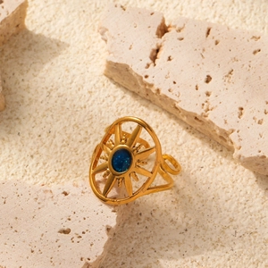 Golden sunburst open ring with hollow design and dark blue enamel center on stone