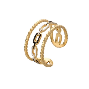 Détail de bague dorée enroulée avec texture torsadée et chaîne en émail noir et blanc