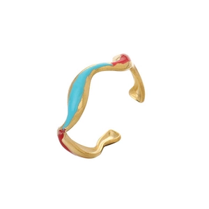 Détail d'une bague ouverte dorée ondulée avec des accents d'émail bleu et rouge