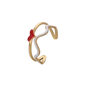 Détail de la bague ajustable dorée avec cœur rouge et motifs de vagues en émail blanc
