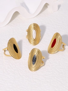 Detail of bohemian gold stainless steel rings with colorful oval inlay on stone surface