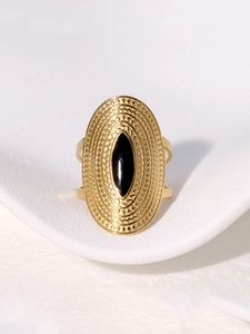 Macro detail of vintage bohemian gold ring with oval texture and black gemstone