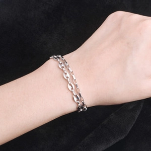 Dettaglio di un bracciale a catena d'argento a strati con design a chicco di caffè al polso