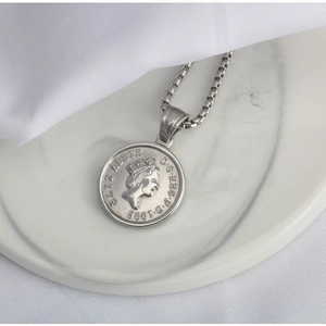 Collana con moneta d'argento vintage con ritratto della regina su base di marmo