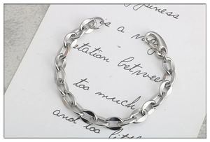 Dettaglio macro del bracciale a maglie in acciaio inossidabile argento su marmo