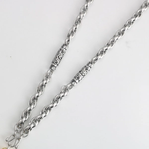Macro shot of silver stainless steel twisted chain with vintage carved cylinders and S-hook