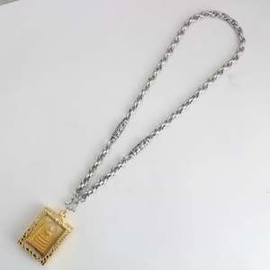 Detail of silver twisted chain with gold Buddha pendant and decorative S-hook clasp