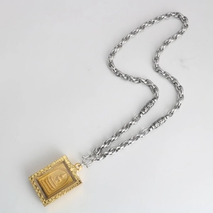 Detail of Thai-style golden Buddha pendant with intricate floral frame on a thick metal chain