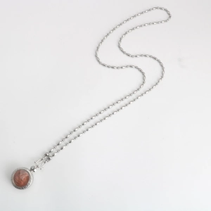 Macro view of stainless steel rice bead chain with a red Buddhist amulet pendant