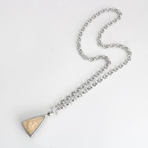 Close-up of a silver stainless steel chain with a carved triangular religious pendant