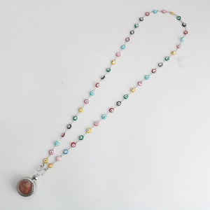 Macro shot of colorful evil eye beads and silver metal pendant on a beaded necklace