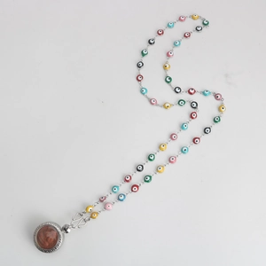 Detailed shot of stainless steel chain necklace with colorful evil eye beads and relief pendant