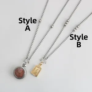 Detail van roestvrijstalen schakelkettingen met ronde en rechthoekige boeddhistische amuletten