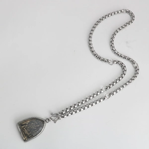 Macro view of a retro stainless steel box chain with a golden deity relief pendant