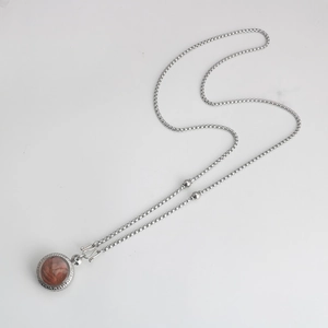 Detail van vintage roestvrijstalen boxketting met rode steen hanger en S-sluiting