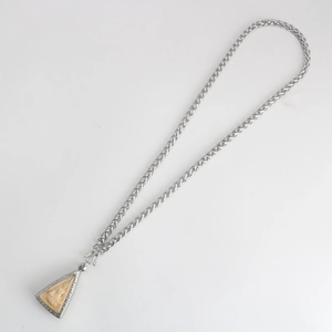 Close-up of silver wheat chain and triangular Thai Buddhist amulet pendant