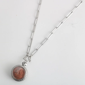 Detail of a Buddhist amulet pendant with reddish relief on silver paperclip chain necklace