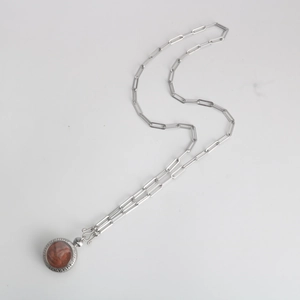 Detail of silver stainless steel paperclip chain with a round religious amulet pendant