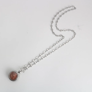 Detail of coffee bean link chain and circular Buddhist relief pendant in silver-tone steel