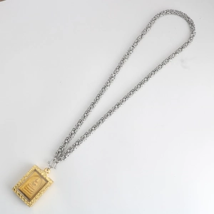 Detailed macro shot of a golden Buddha pendant with heavy duty silver stainless steel chain