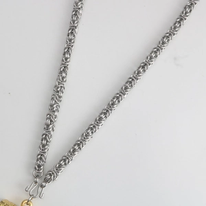 Detailed macro view of silver Byzantine weave stainless steel dragon chain necklace link